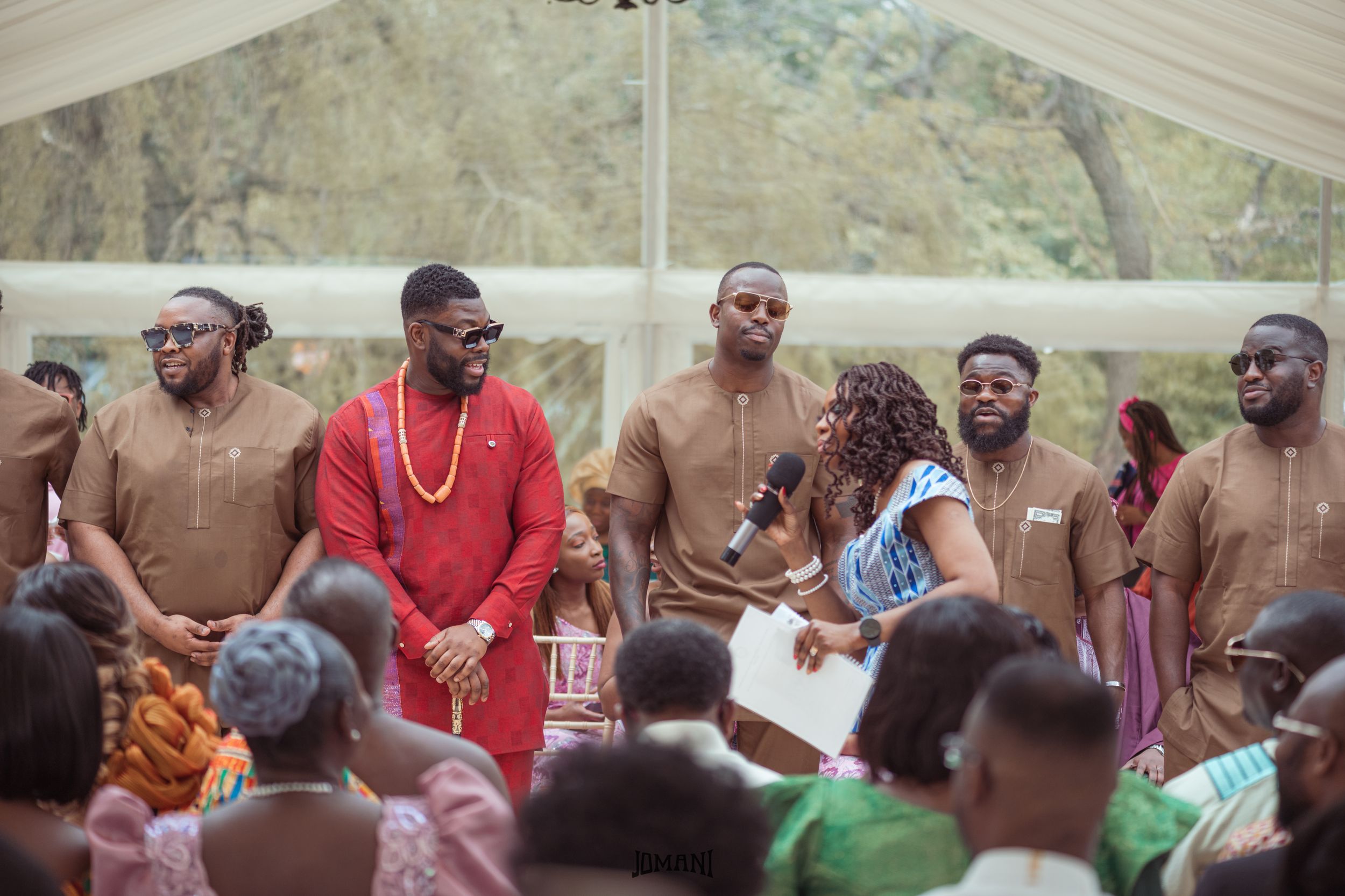 Group of men in matching brown outfits at a traditional African wedding celebration.