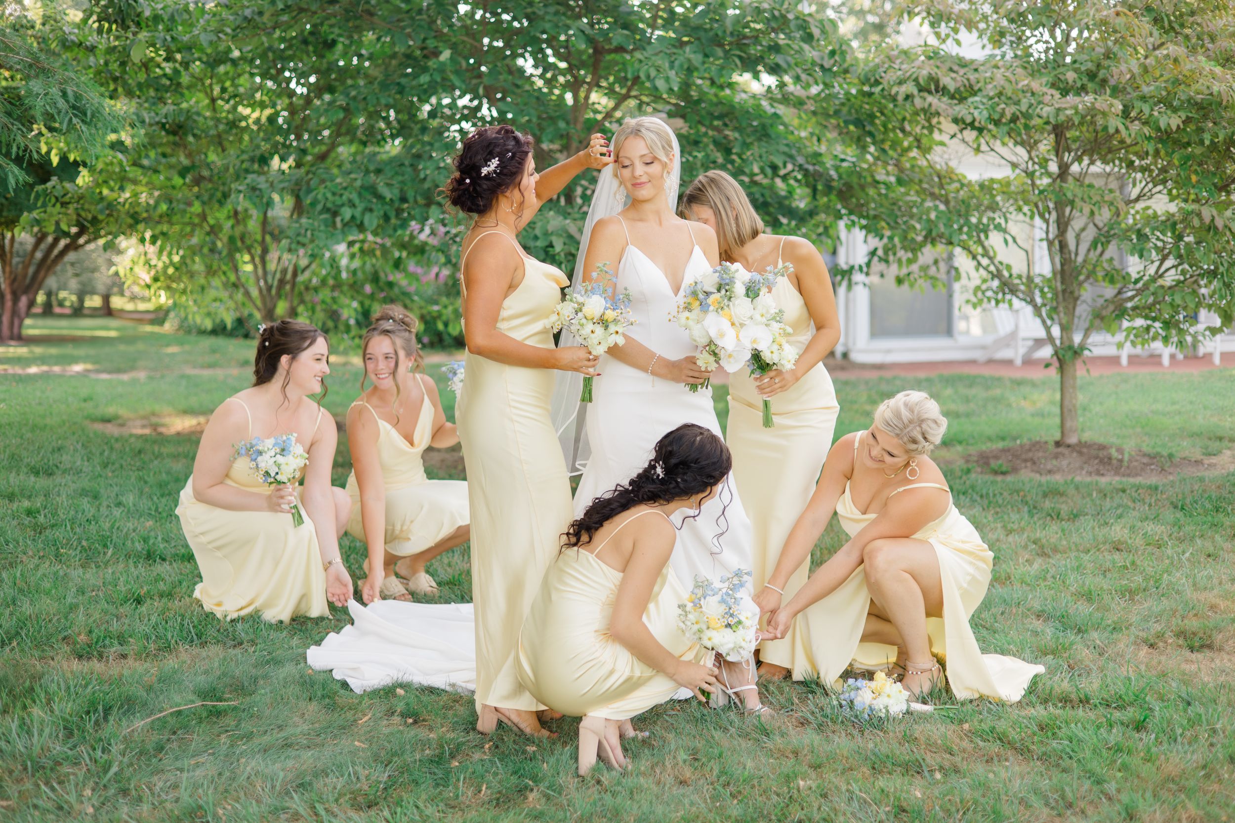 Bridesmaids helping bride get ready in lush green garden