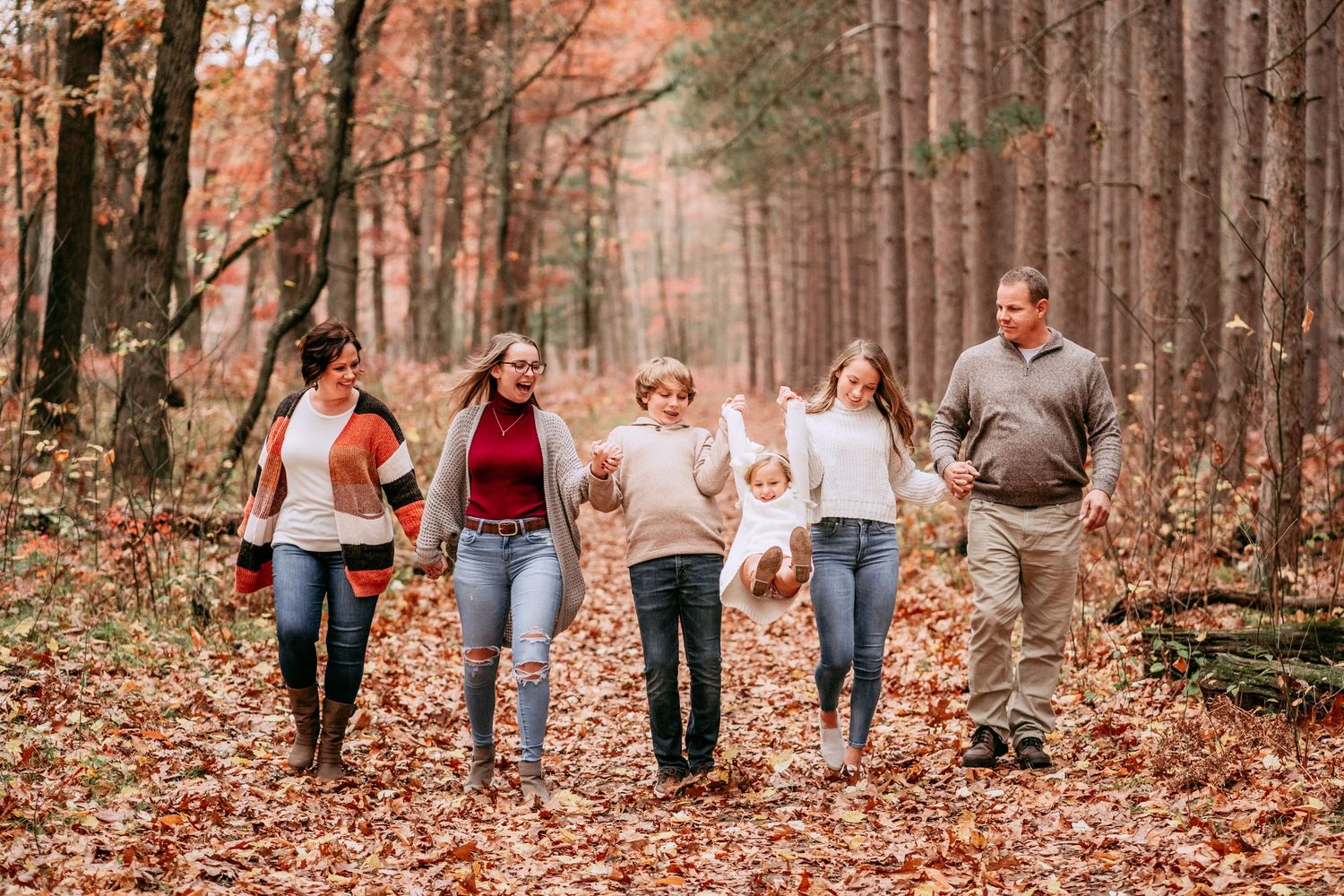 Group walking through autumn forest with fallen pine needles covering the ground.