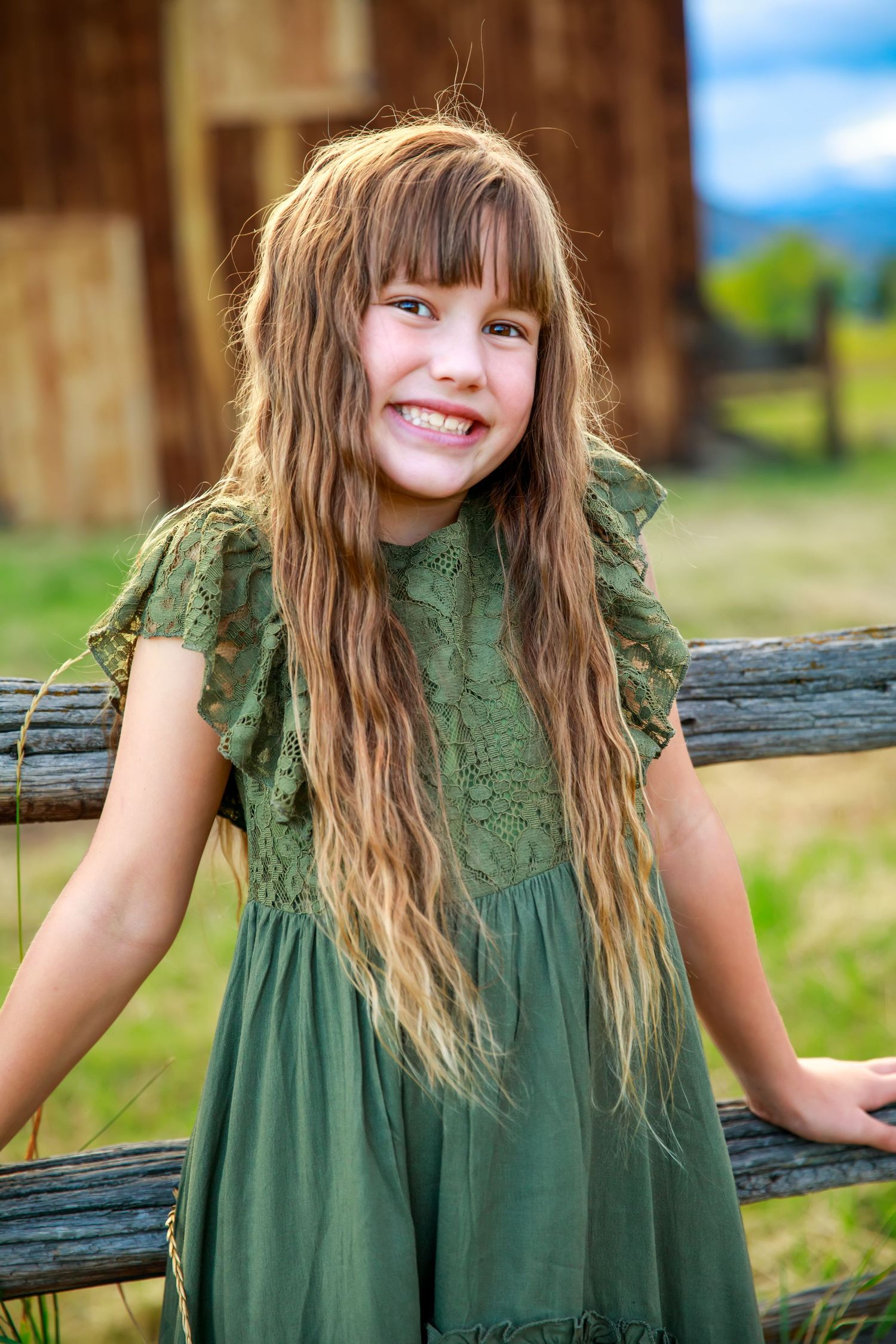 A series of photos showing someone in a green lace dress posing against a rustic wooden fence outdoors.