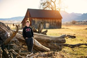 Rural portrait session with rustic barn and mountain scenery at golden hour.