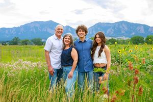 Scenic outdoor countryside family photo session with mountains and wildflowers in the background.