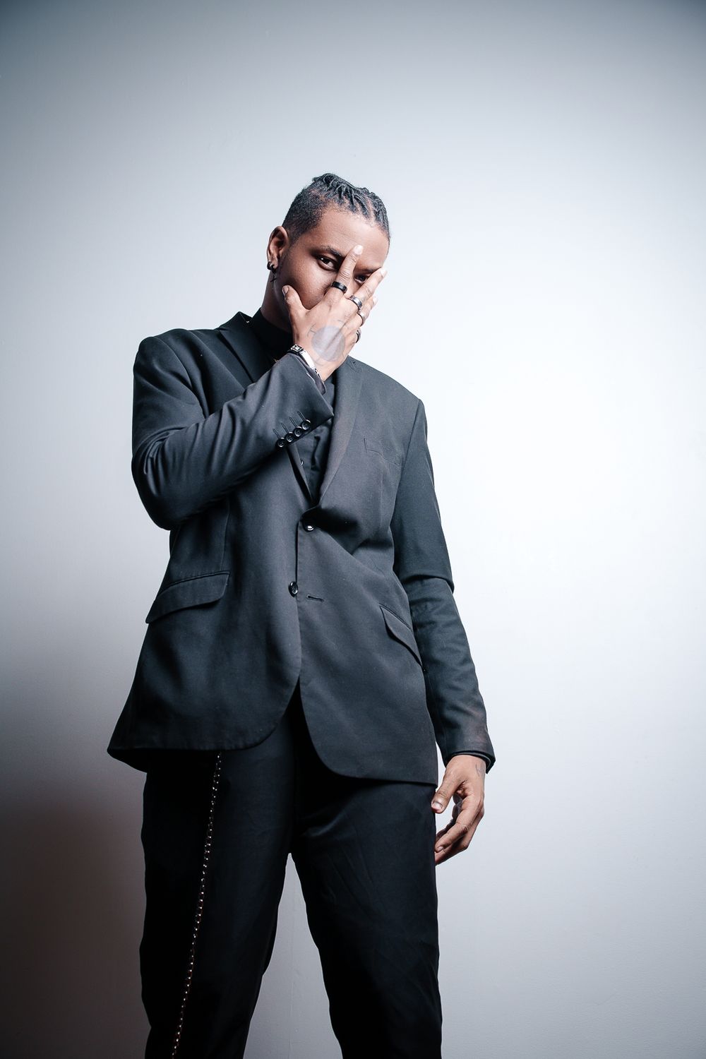 A person in a dark business suit covers their face with their hand in a series of expressive poses against a white background.