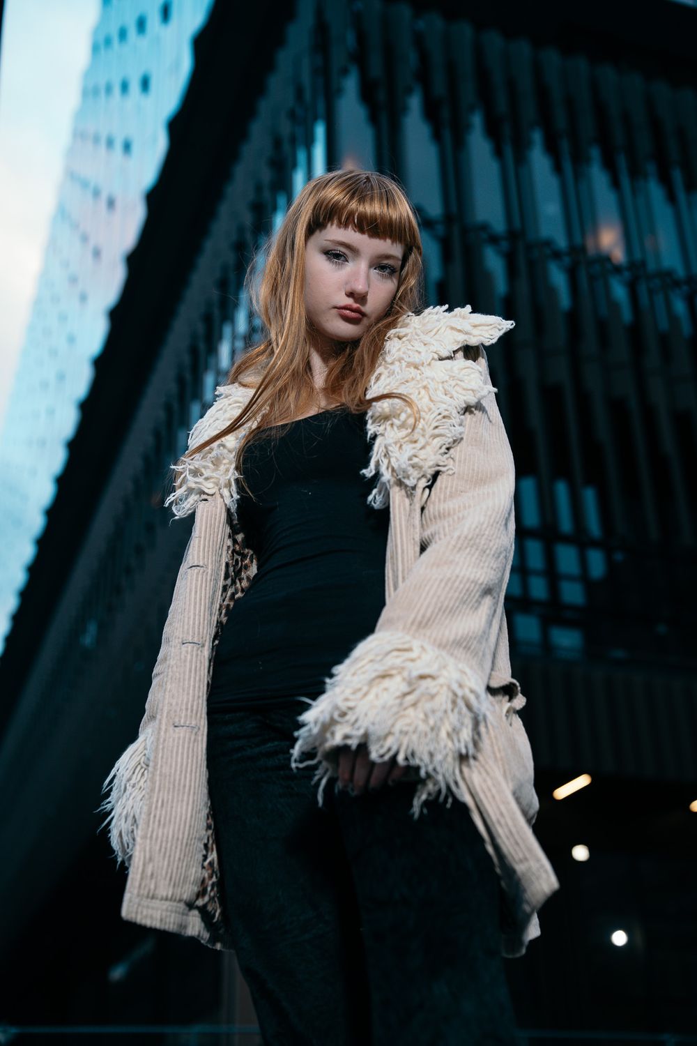 Street fashion photo featuring model in textured cream cardigan against urban backdrop.