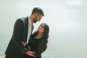 A couple shares an intimate moment against a misty waterfront backdrop.