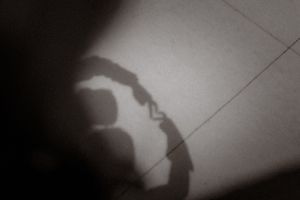 Moody black and white shadow silhouette of two figures embracing against a wall.
