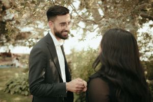 Elegantly dressed couple having intimate conversation in garden setting.