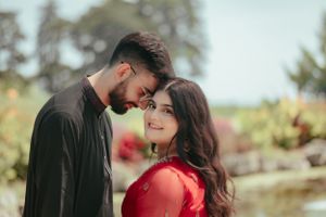 Couple in casual attire sharing tender moment in sunny garden setting.