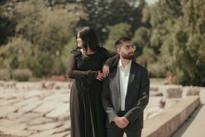 Artistic portrait of couple in contrasting outfits against natural backdrop.