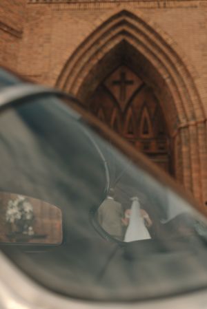 Blurred motion shot of a bride and groom walking under an ornate church archway with gothic architectural details.