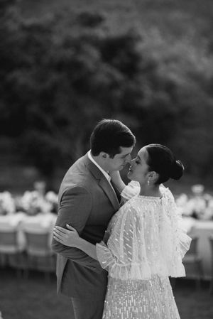 A couple shares a romantic kiss in a black and white outdoor wedding photo series.