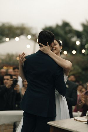 A romantic wedding ceremony moment captured at dusk with string lights glowing in the background.