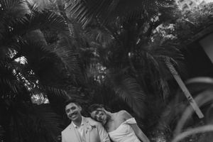 Black and white portrait of a couple sharing a joyful moment among tropical palm trees.