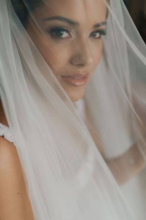 Close-up portrait through delicate white veil on wedding day.
