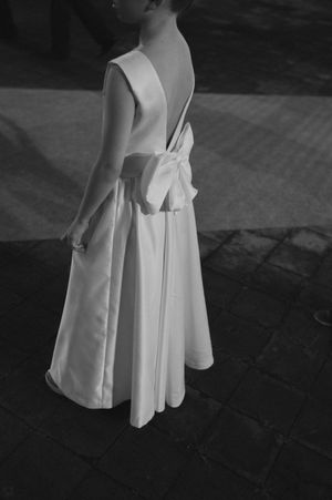 Close-up views of a white pleated dress with spaghetti straps shown from different angles on a dark surface.