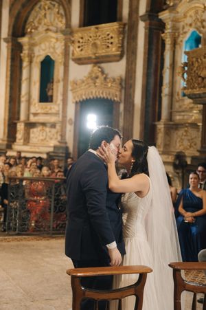 A romantic wedding kiss in an ornate church with golden baroque details and stone columns.