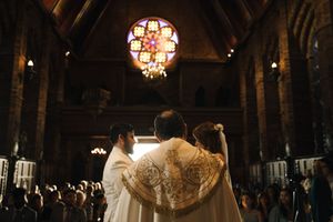 Elegant wedding reception venue with ornate chandeliers and guests seated at long tables in a dimly lit room.