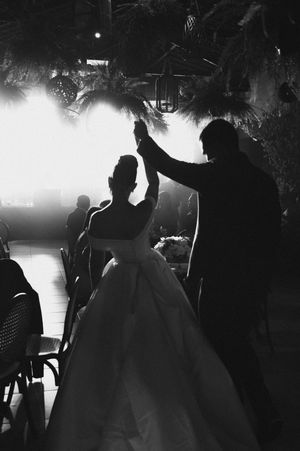 A dramatic silhouette of a wedding dance with backlighting creating an atmospheric scene at a reception.