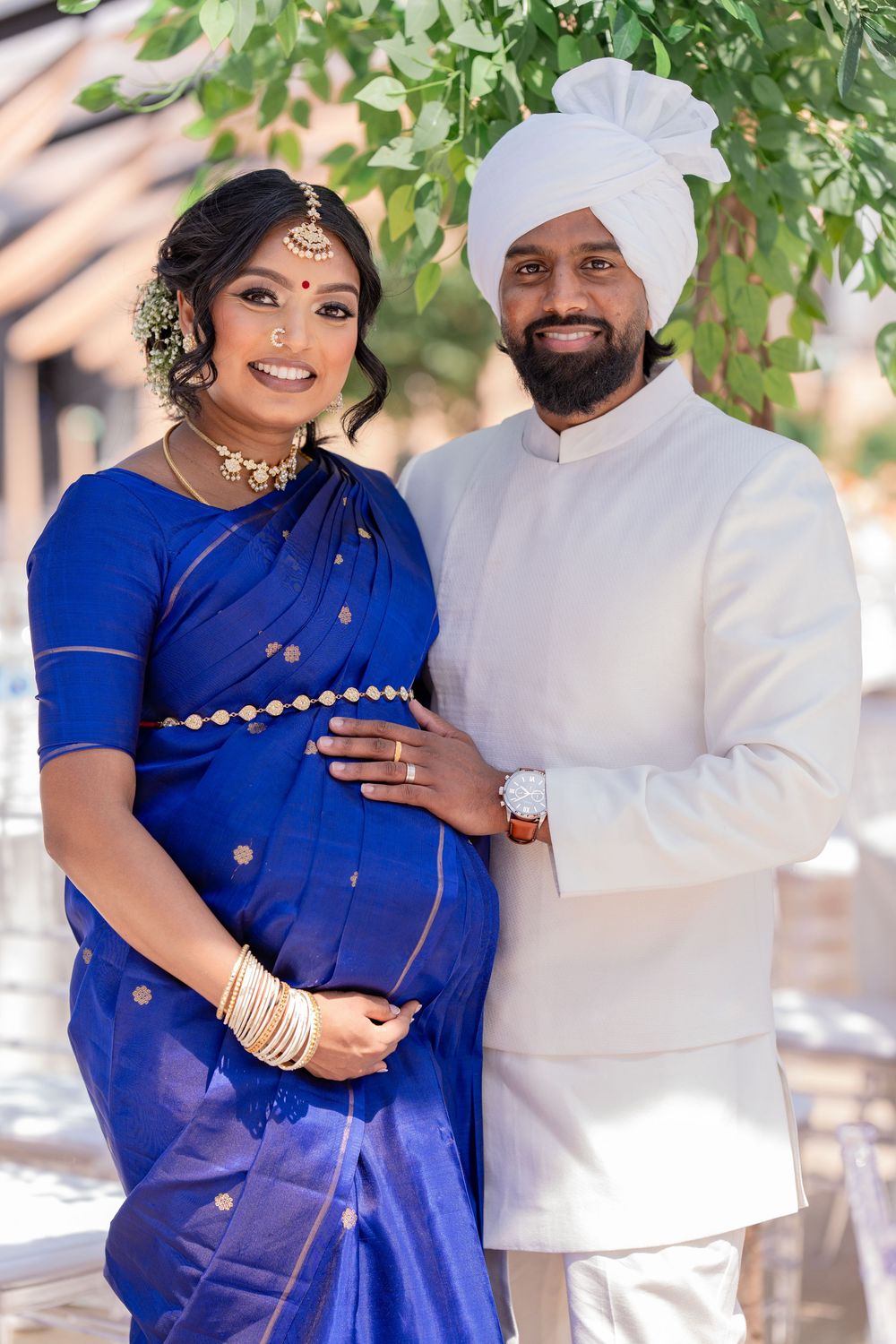 Couple expecting their first baby in traditional Thamizh attire; the woman is in a blue saree and her husband in a white kurtha.
