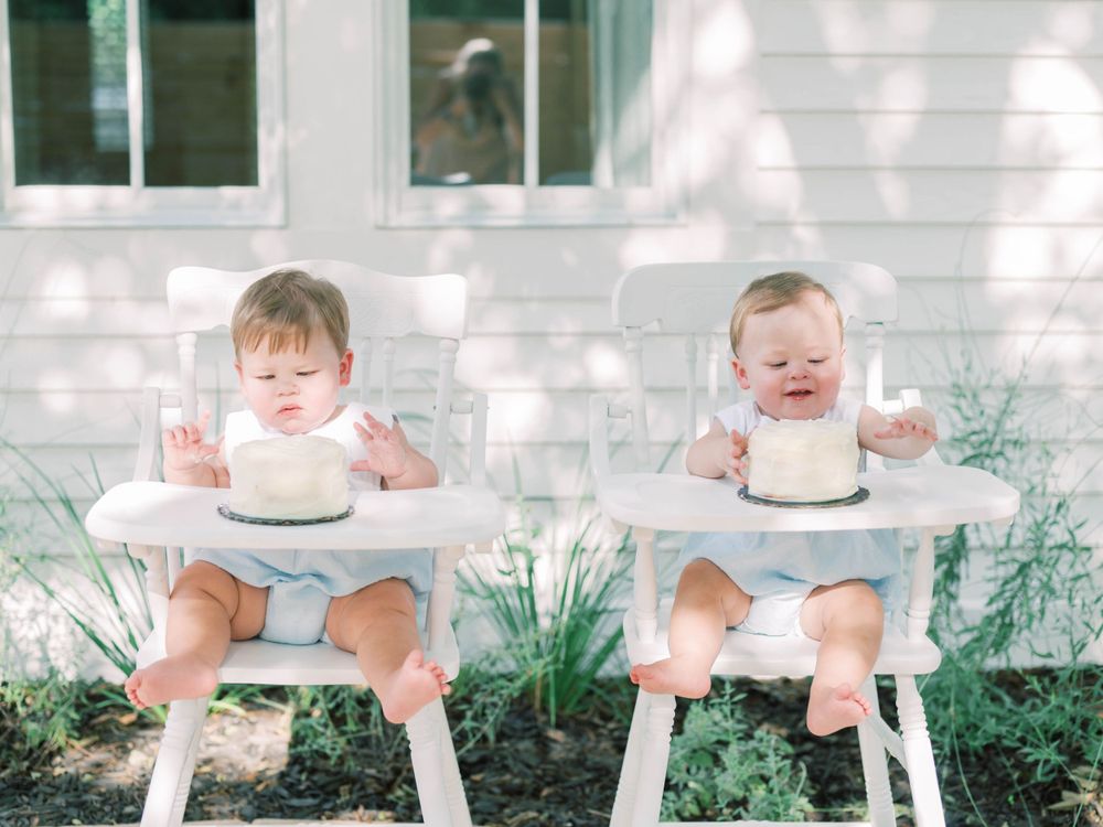 milestone session with twin boys turning one with cakes in highchairs