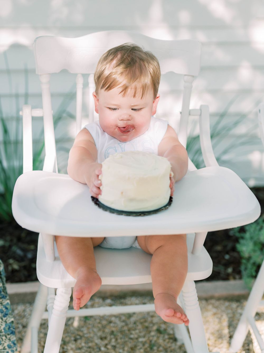 milestone session of a one year old cake smash and baby boy licking his lips
