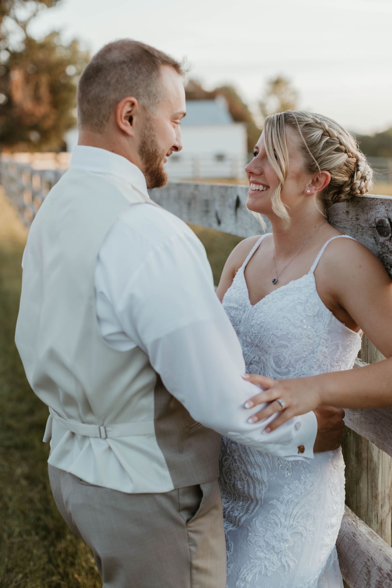 Romantic outdoor wedding portraits showing tender moments between newlyweds by a wooden fence.