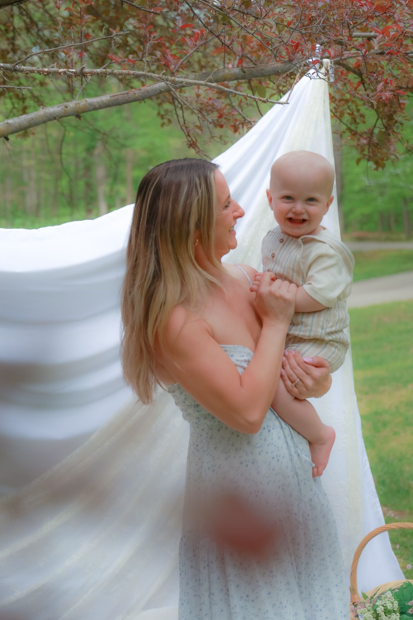 Joyful outdoor family photos with white fabric backdrop and blooming trees.