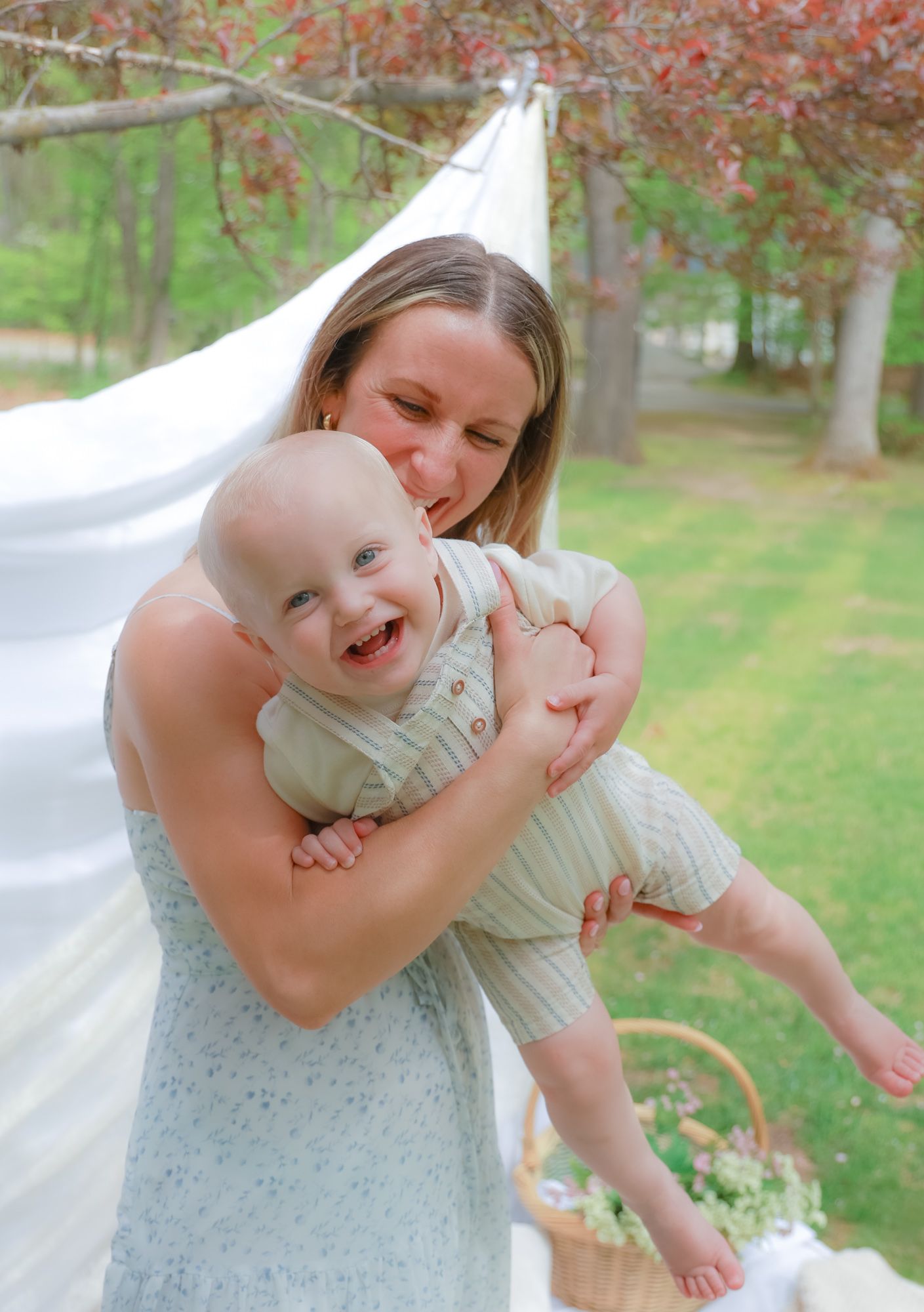 Playful mother and baby moments captured against white backdrop outdoors.