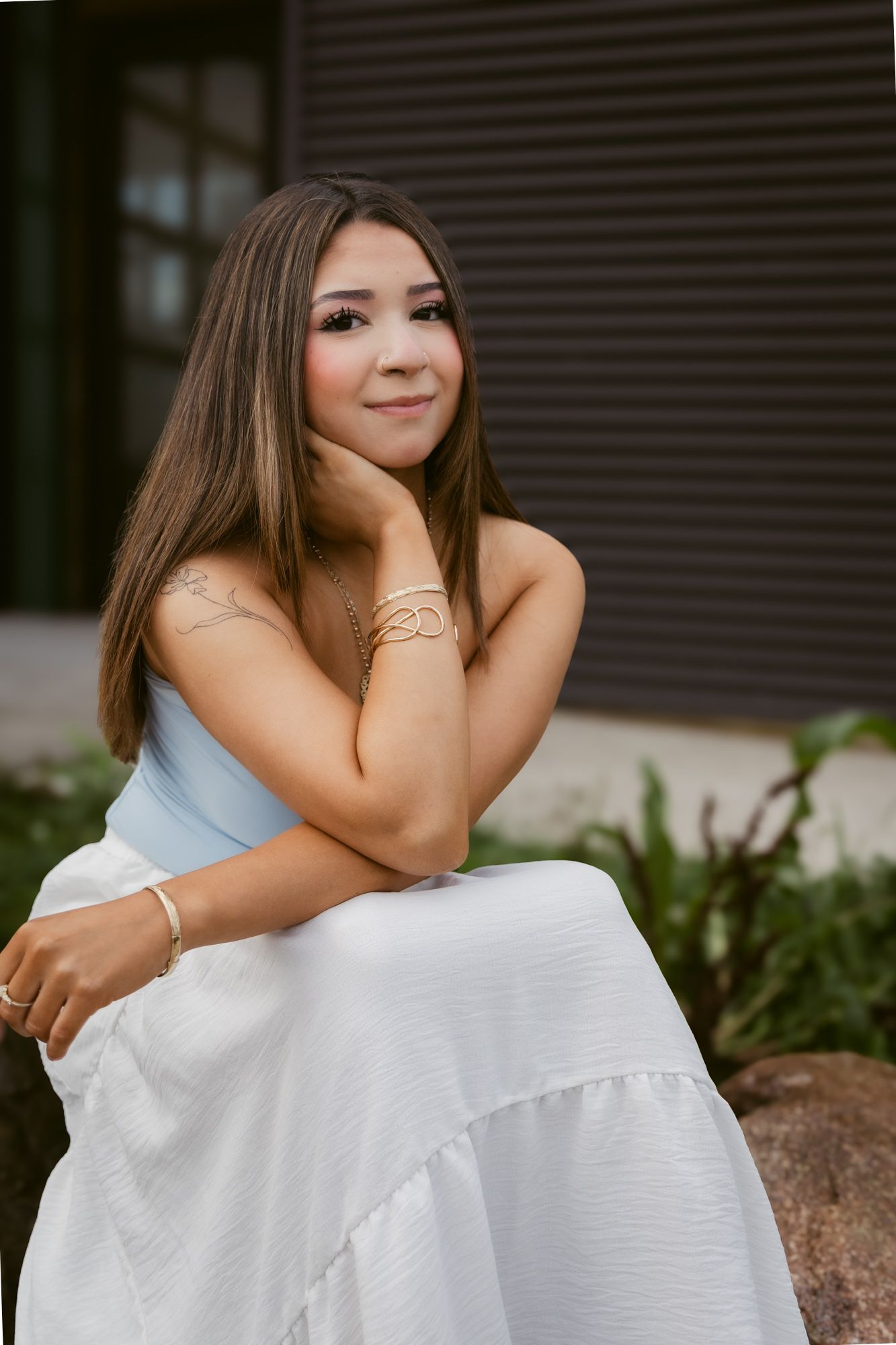 A series of portraits showing someone in a white dress sitting outdoors against a dark architectural background.