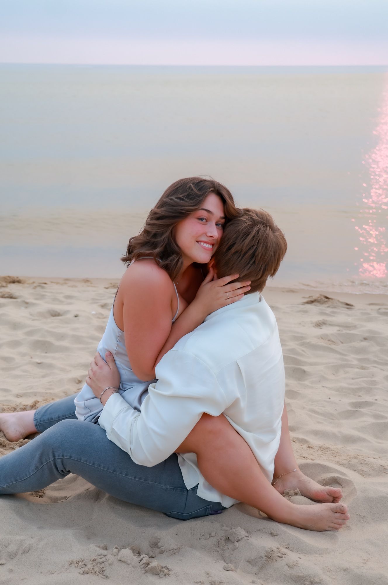 Couple sharing intimate moments while lying on sandy beach at sunset.