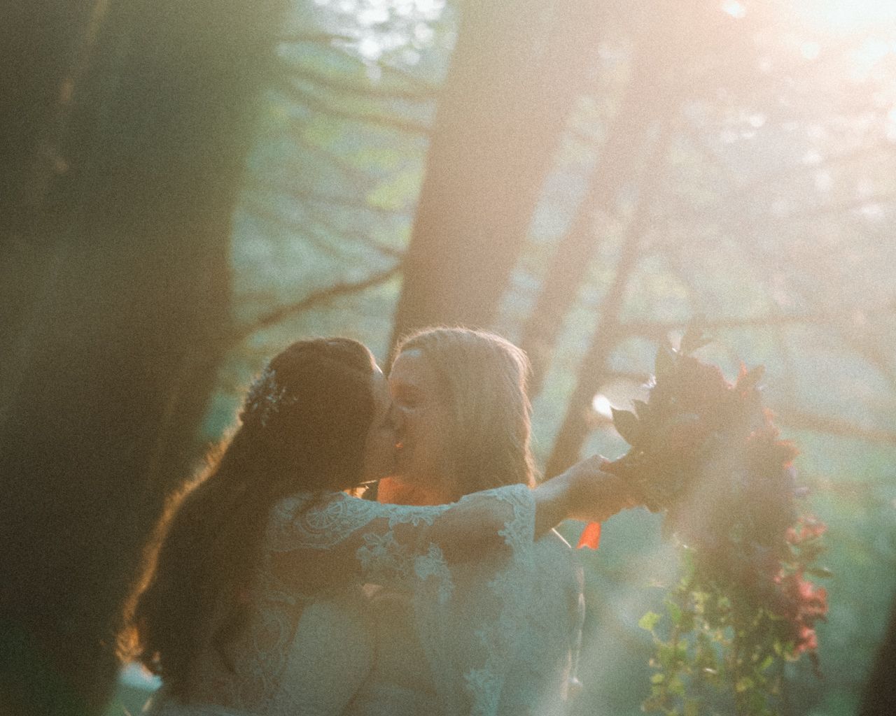 A sun-drenched outdoor scene showing an intimate embrace between two people.