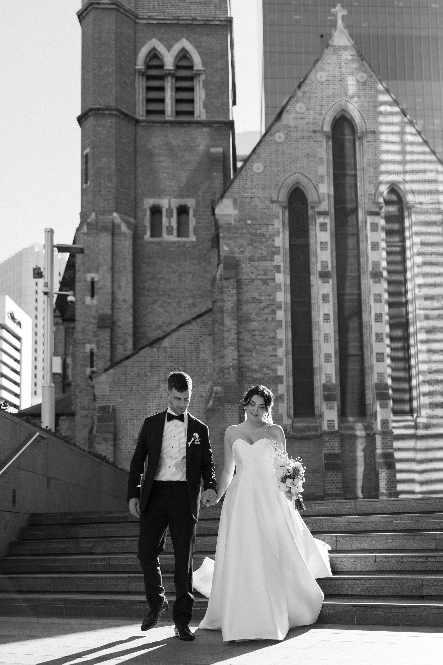 A series of black and white wedding photos showing a couple walking in front of a Gothic church with tall spires.
