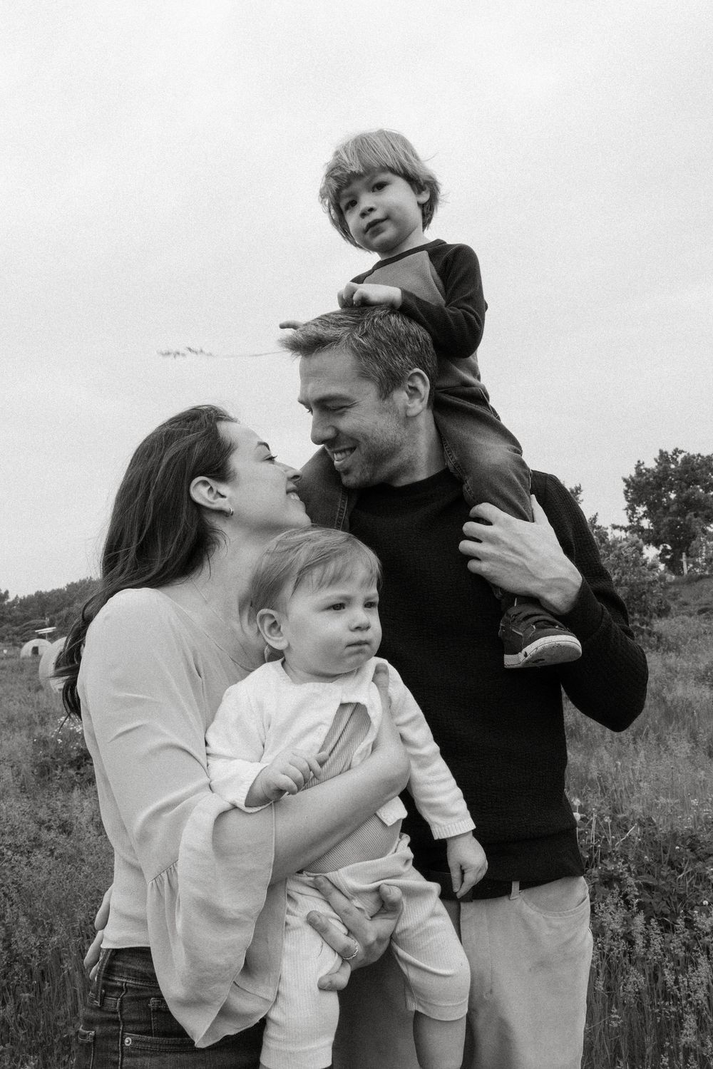 A loving family moment captured in black and white as they embrace in a field of wildflowers.