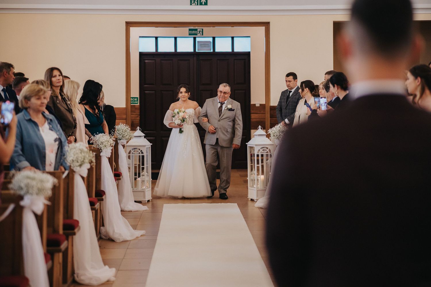 panna mloda wchodzi z tata do kosciola. Mlody juz czeka na nia pod ołtarzem. Wojciech Grzegorczyk fotograf ślubny