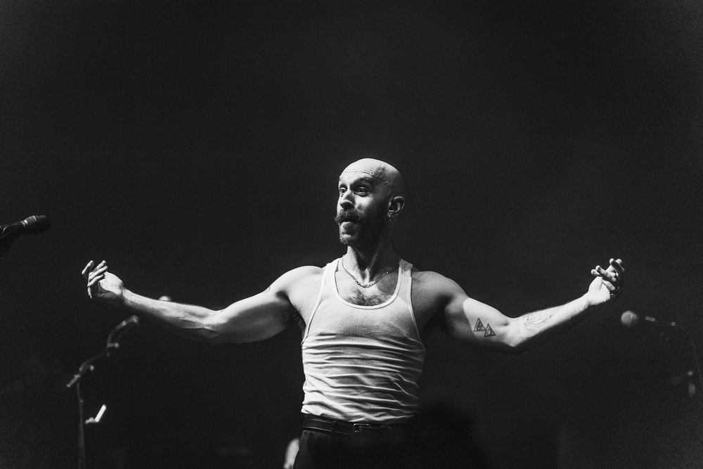 Dramatic black and white shot of performer with outstretched arms on stage.