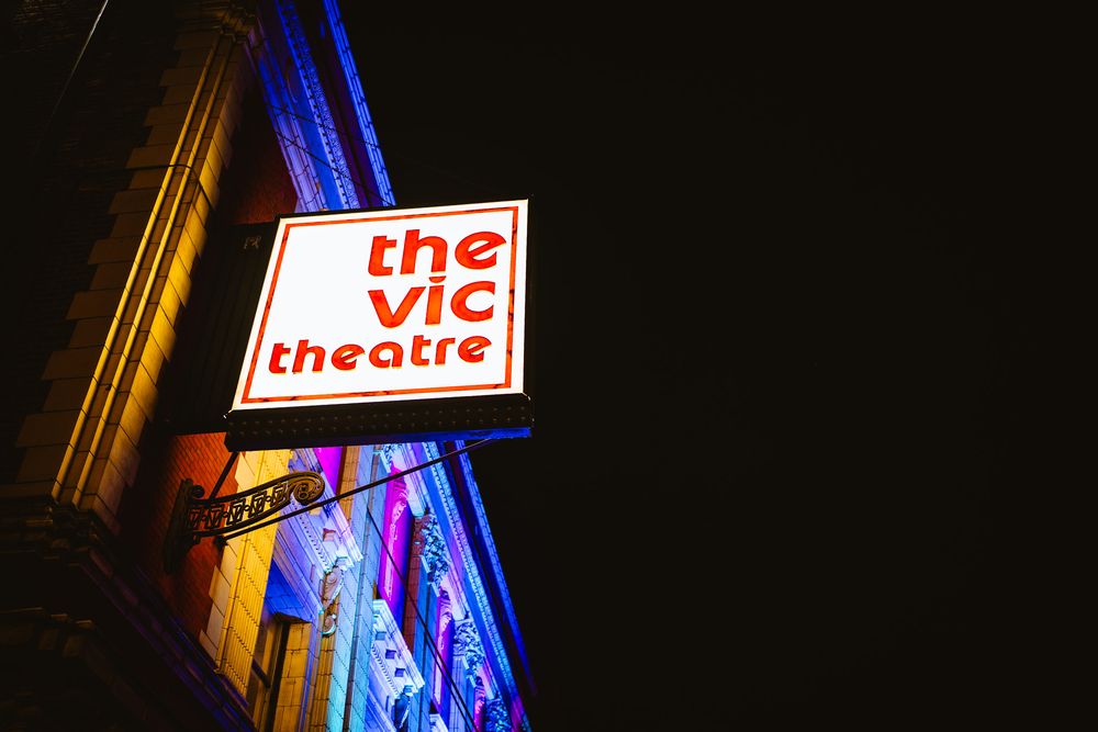 Illuminated theater sign glowing in blue and red against night sky.