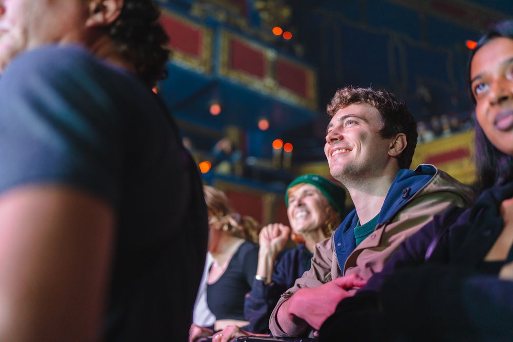 Crowd enjoying an entertainment event in a dimly lit venue with colorful ambient lighting.