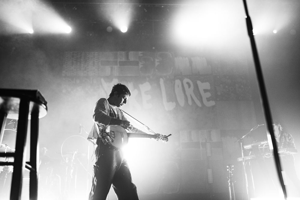 Black and white concert performance with dramatic stage lighting and silhouettes.