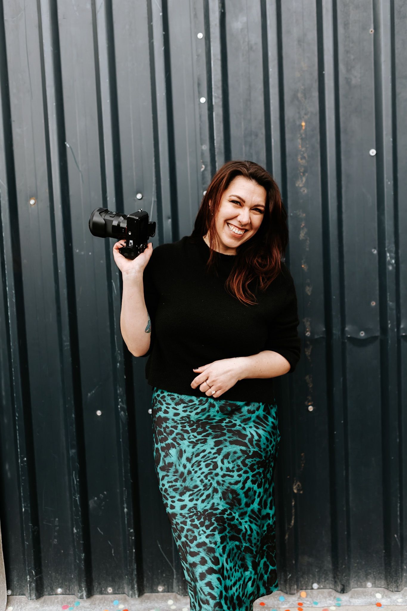 Fashion portraits against industrial metal wall showing teal leopard print skirt and black top.