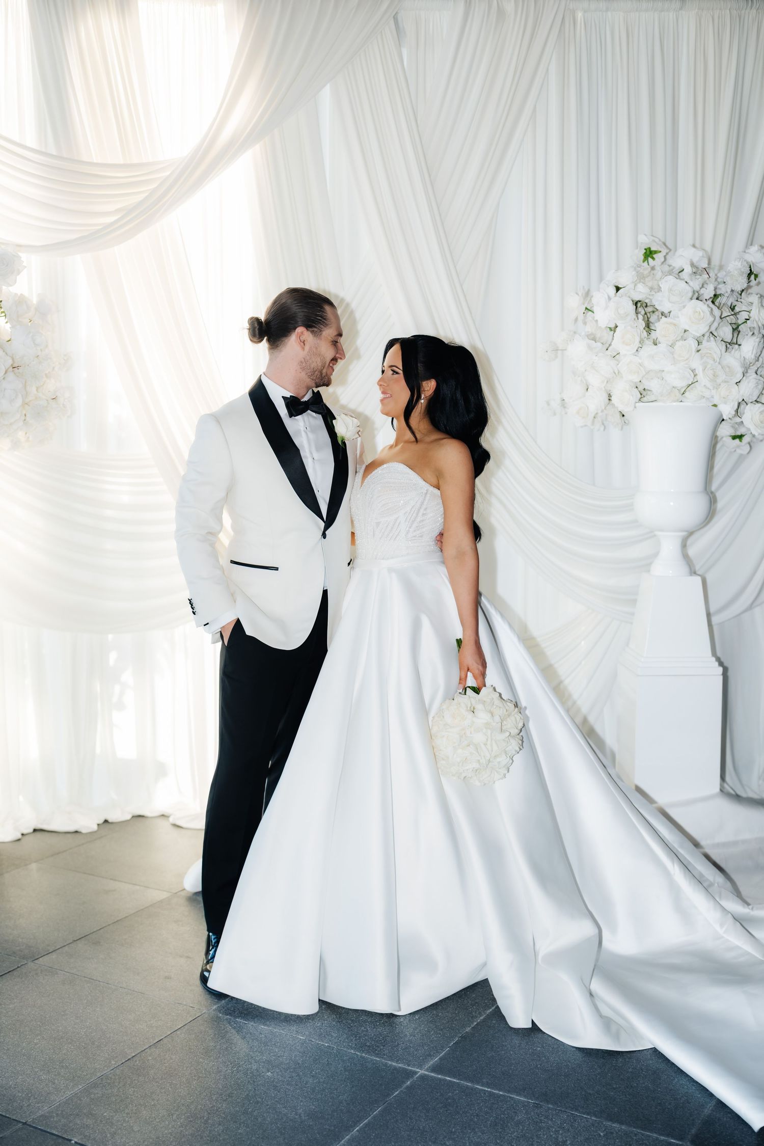 Beautiful bride in white lace mermaid wedding gown and veil poses with bouquet for Vogue magazine cover.