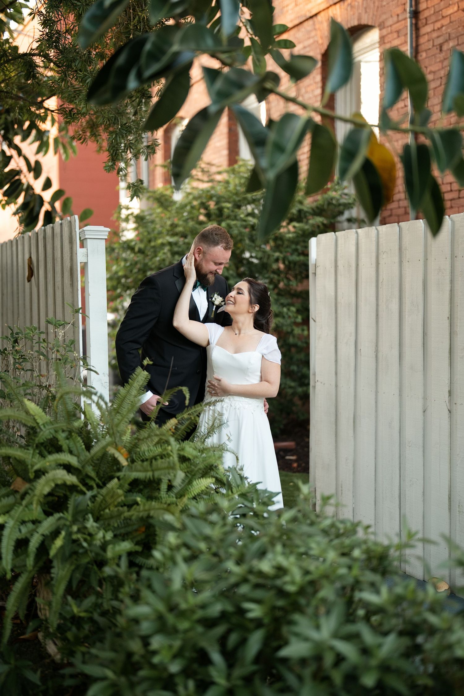 Bride in white gown with long veil stands at outdoor wedding altar with groom and groomsmen in black tuxedos.