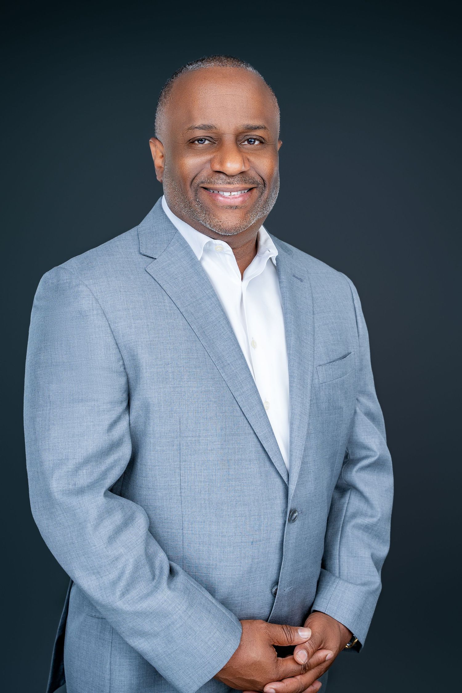 Professional business portrait in light gray suit jacket with white collar shirt.