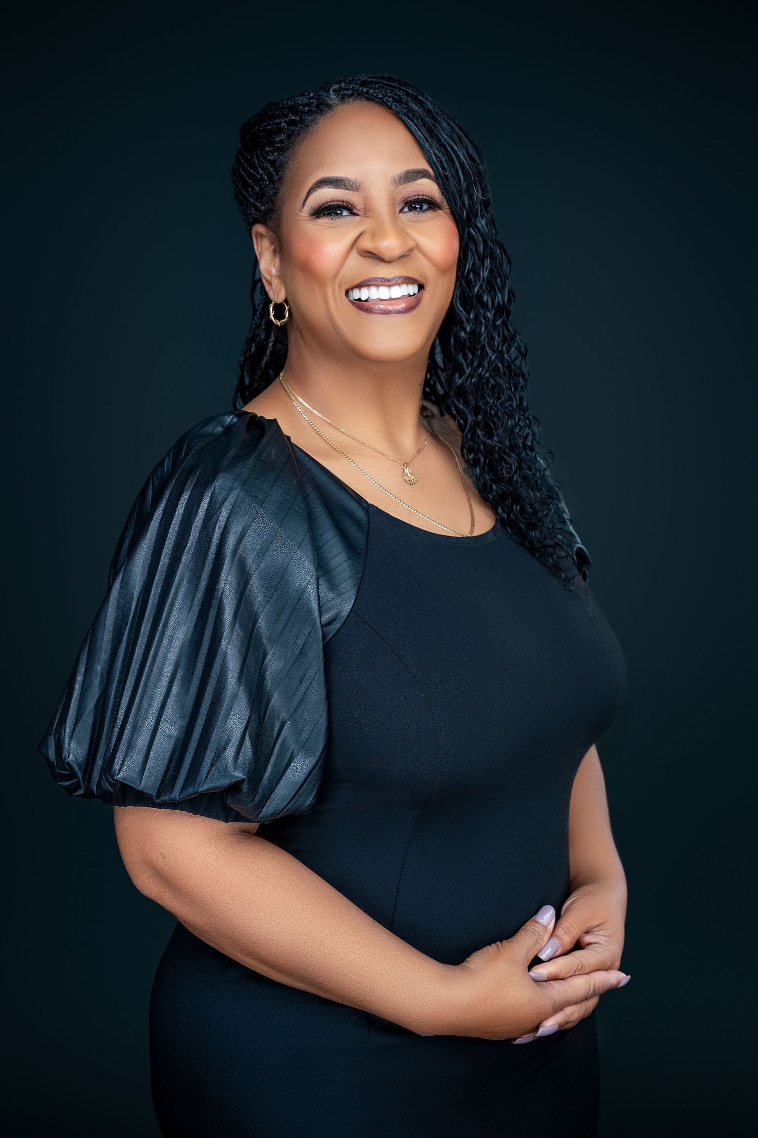 Professional studio portrait in black top with puff sleeves against dark background.