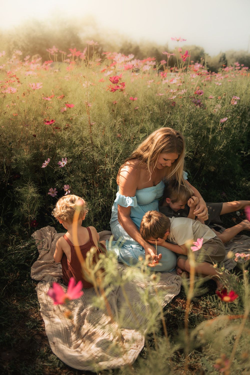 Three friends relax in a dreamy wildflower meadow with red blooms on a sunny afternoon.