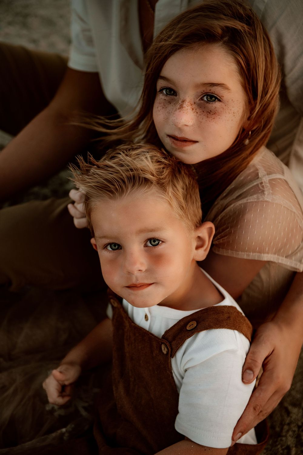 An intimate indoor portrait featuring warm lighting and earth-toned clothing.