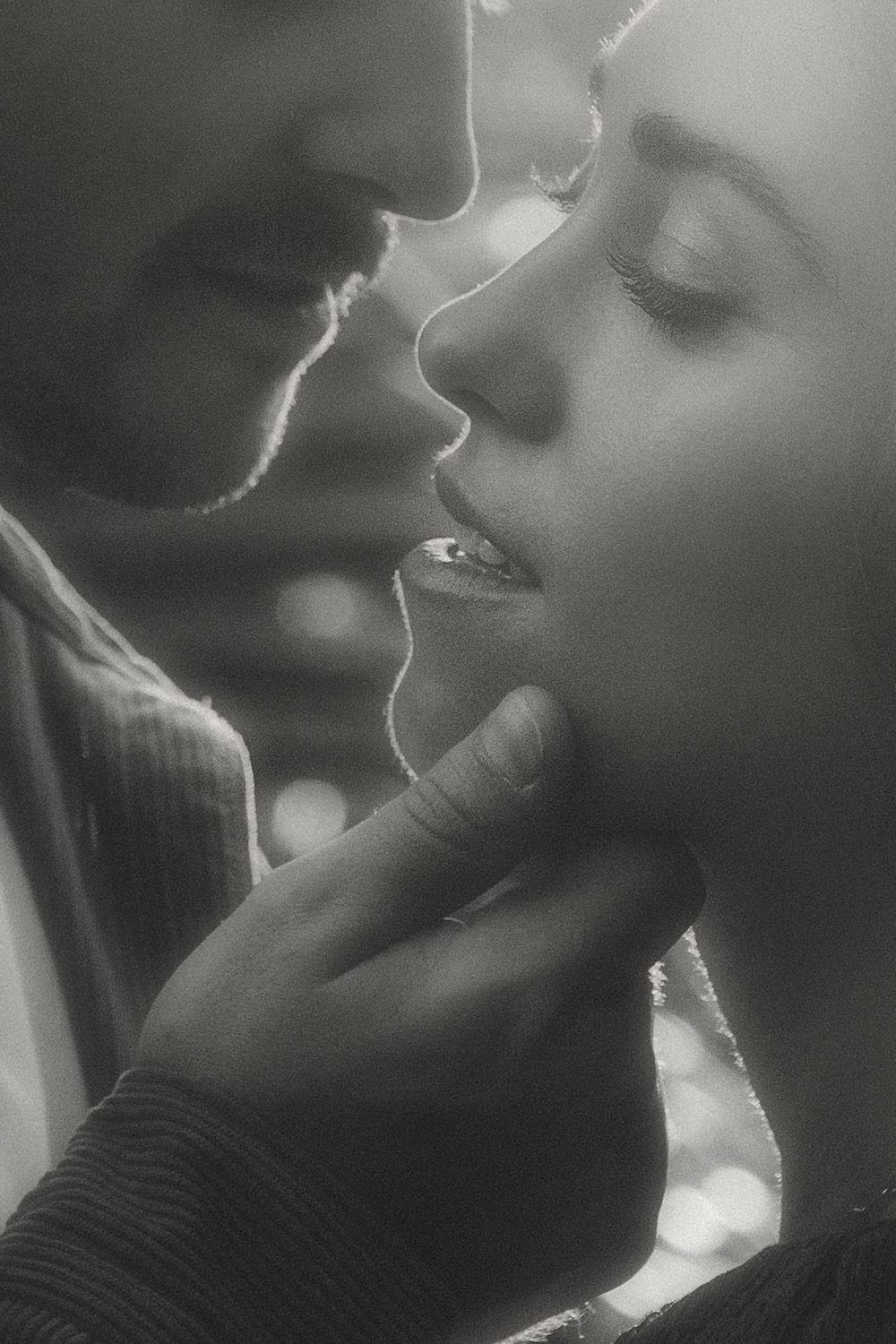 Dramatic black and white close-up profile shots showing a couple in an intimate moment with soft lighting and shadows.