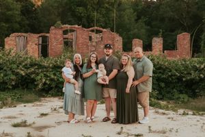 A group poses for a photo in front of rustic brick ruins at sunset.
