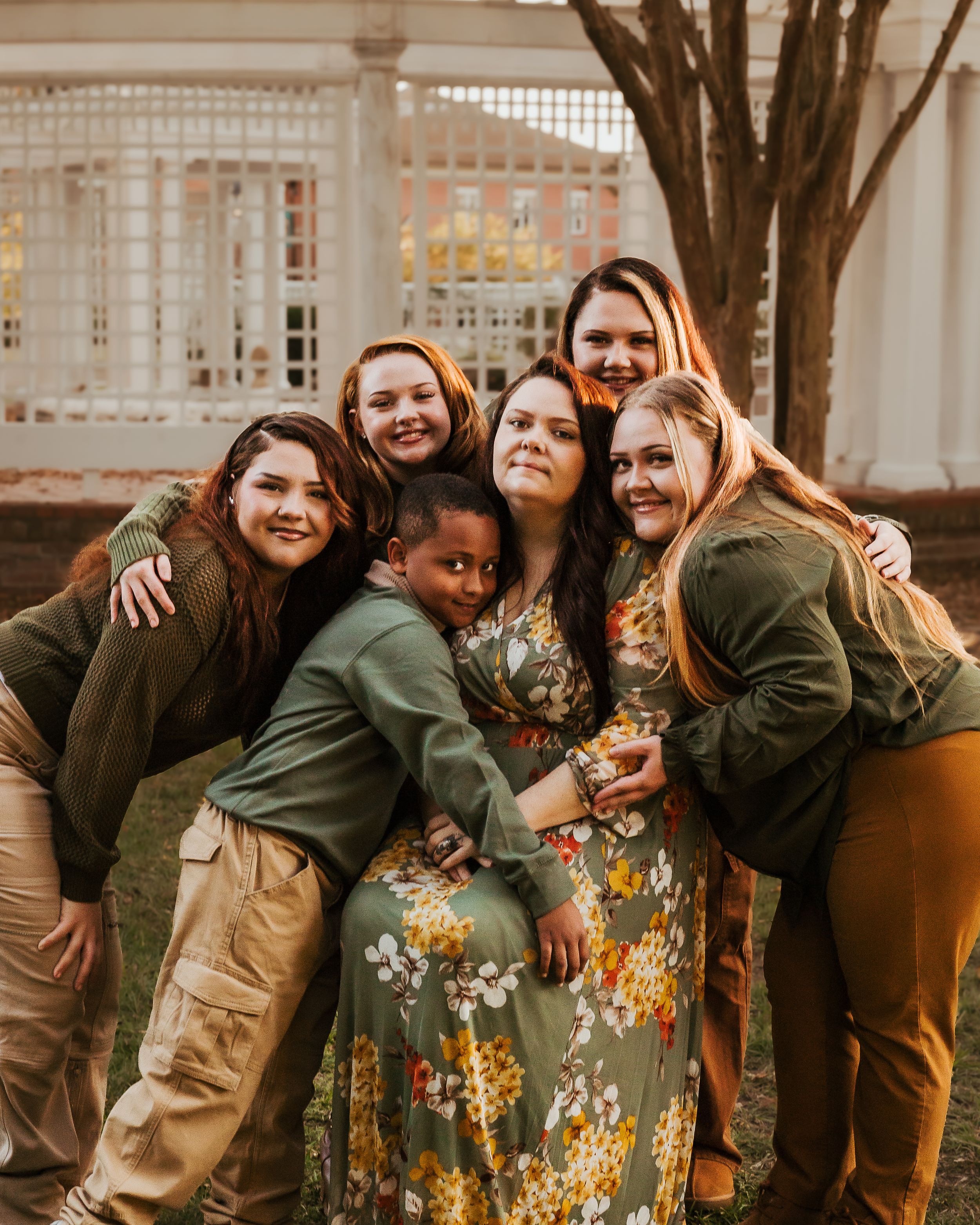 A group of friends pose together outdoors wearing floral dresses and casual attire.