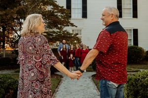 A couple holds hands while sharing a moment together on a church walkway.