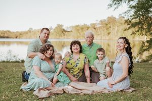 A multi-generational family gathering for a portrait by a lake at sunset.